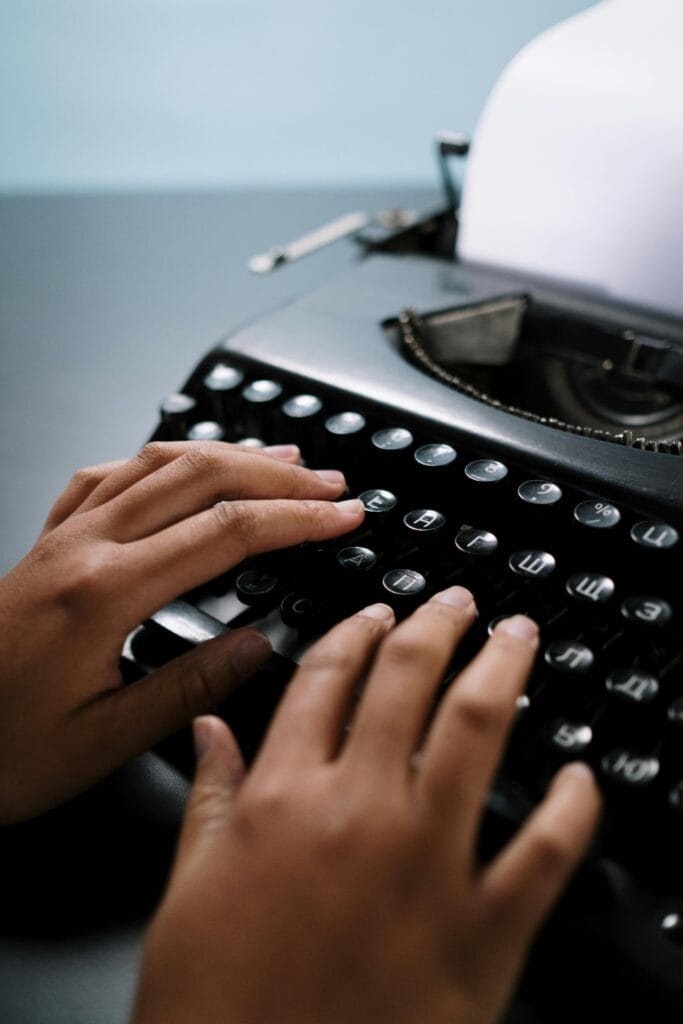 Hands typing on a classic black typewriter, emphasizing retro technology.