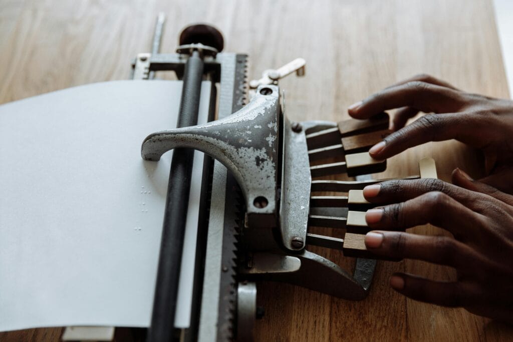 Close-up of hands using a braille typewriter, highlighting accessibility tools.